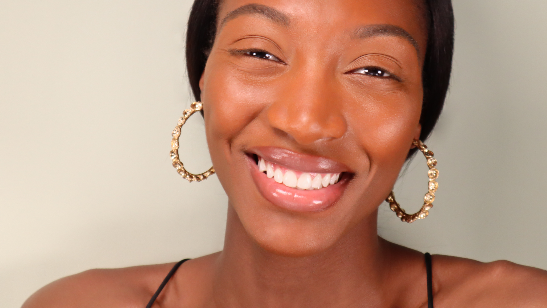 Model wearing large hoop earrings in gold smiling 